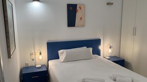 A hotel room with a bed, two bedside tables, a wall-mounted artwork, and a wardrobe.