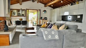 A modern living room with a grey sofa, a wooden coffee table, and a dining area with a white table and chairs.