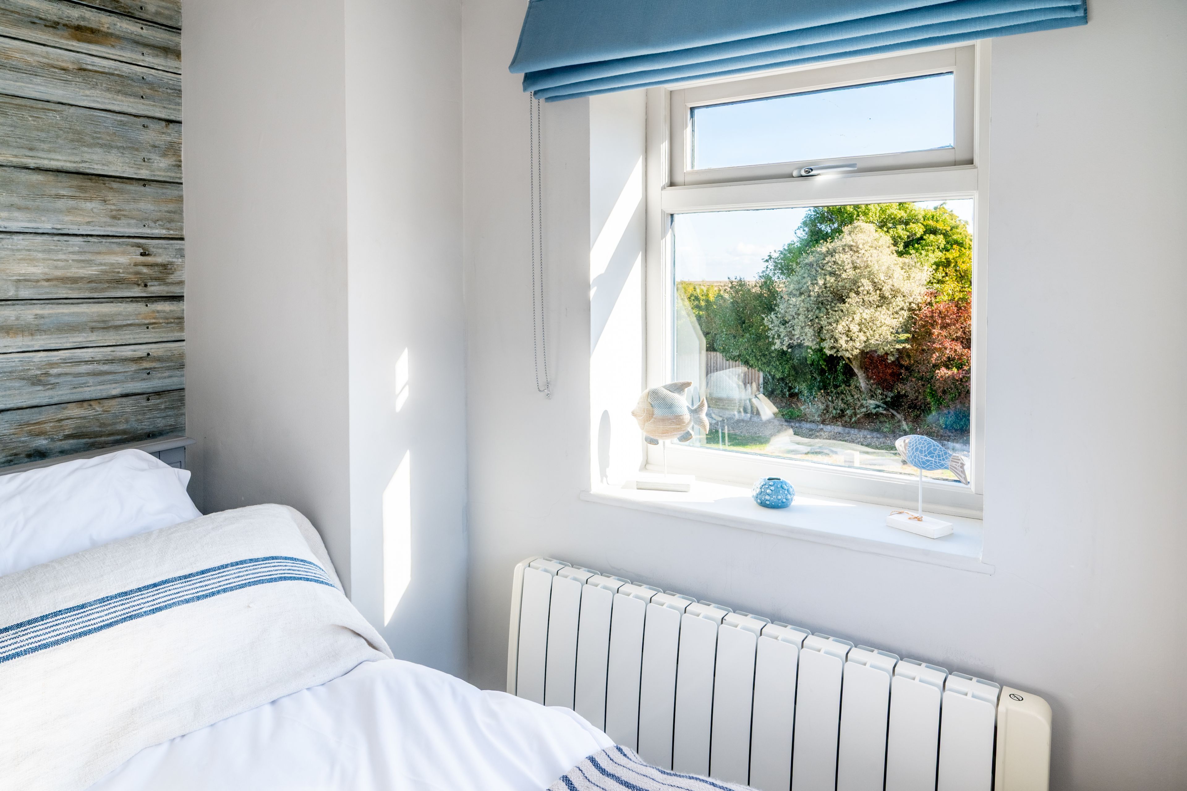 A bedroom with a bed, a window with a view of trees, and a radiator.
