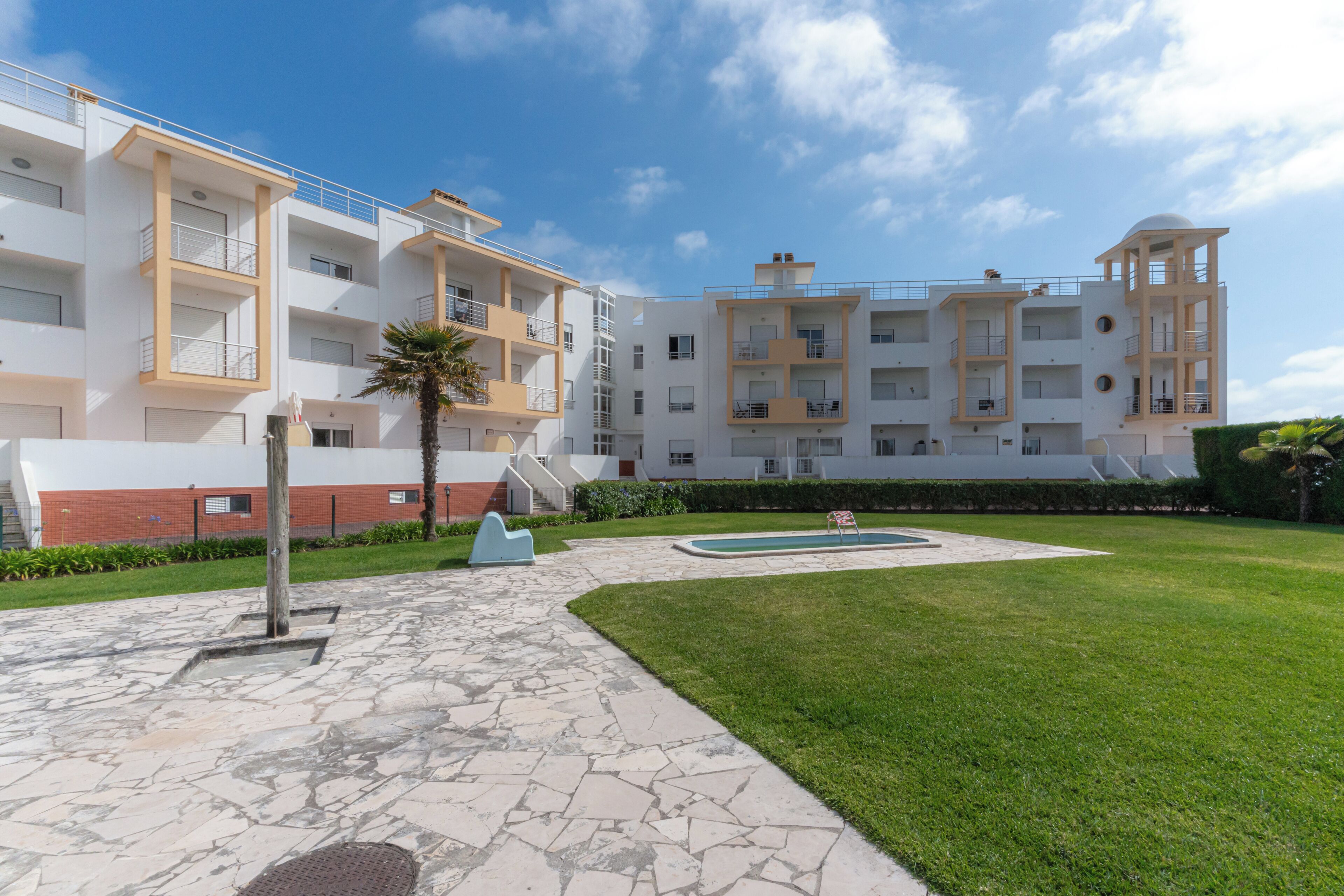 Un immeuble d’appartements moderne doté de nombreux balcons, d’une piscine et d’une pelouse bien entretenue.