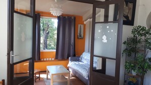 A room with a sofa, a table, a window with curtains, and a plant. - "MarViva" Air-conditioned house, 2/3 bedrooms - Private swimming pool, 5 min walk to the beach (La Seyne-Sur-Mer)