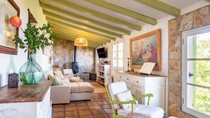 A cozy living room with a stone wall, a green chair, a sofa, and a wooden table.