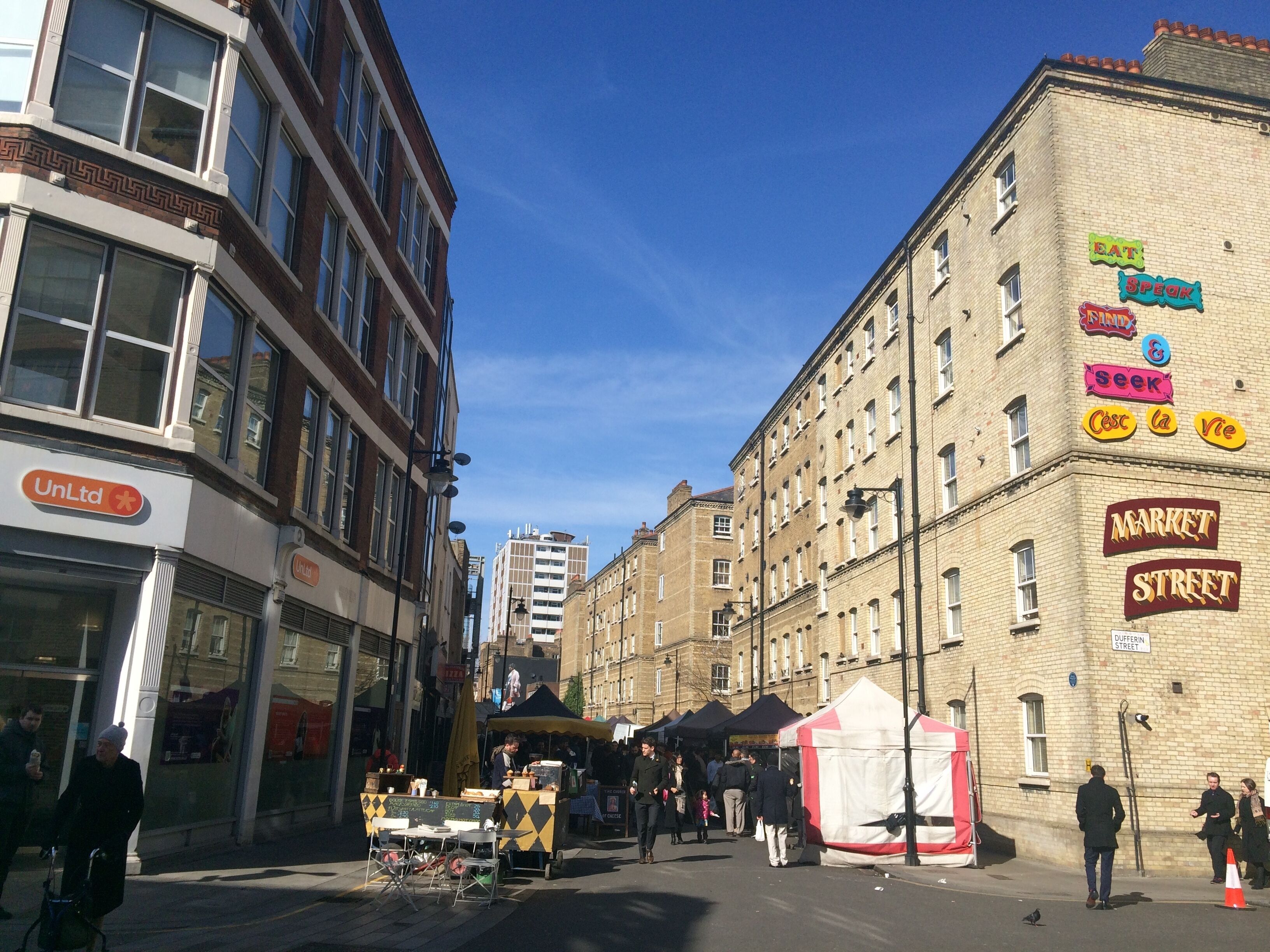 A street with buildings, a market street sign, and a tent.