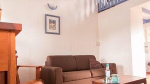 Una sala de estar con un sofá marrón, una mesa de centro de madera y un ventilador de techo.