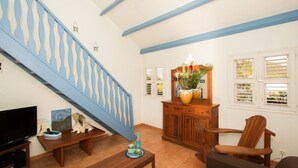 Una sala de estar con una escalera azul, un armario de madera con un espejo, un televisor y una planta.