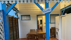 Un patio con mesa y sillas de madera, una parrilla y un letrero que dice "Kanari Bleu".