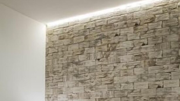 A bedroom with a stone-patterned headboard, a bedside table with a lamp, and a bed with a dark-colored blanket. - Rural Apartment El Rellotge for 6 people (Sant Mateu)