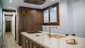 A kitchen with wooden cabinets, a stainless steel range hood, a sink with a brass faucet, and two wine glasses on a marble countertop. - Rural Apartment El Rellotge for 6 people (Sant Mateu)