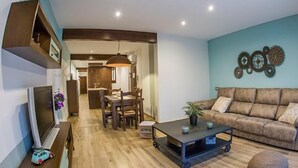 A modern living room with a wooden floor, a sofa, a coffee table, and a TV on a stand. - Rural Apartment El Rellotge for 6 people (Sant Mateu)