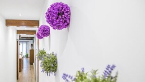 A hallway with wooden flooring, white walls, and purple floral decorations. - Rural Apartment El Rellotge for 6 people (Sant Mateu)