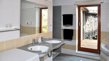 Een bad/douchecombinatie, een haardroger, handdoeken, zeep