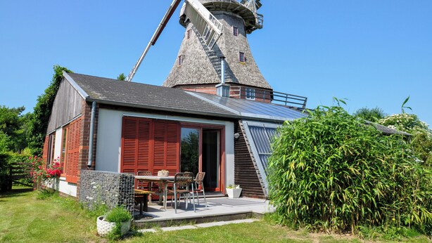 Eine traditionelle Windmühle mit angebautem modernen Haus.