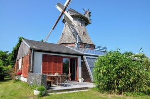 Een klassieke windmolen met een moderne woning ernaast.