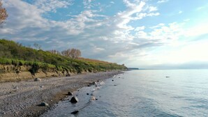 Ein Kiesstrand mit einer grünen Hügelsicht und blauem Himmel.