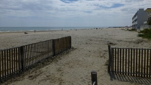 Ein Strand mit einer Holzlattenveranda und einem Gebäude im Hintergrund.