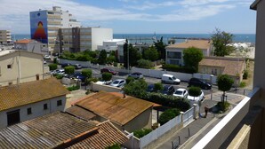 Ein Küstenabschnitt mit Gebäuden, parkenden Autos und Blick auf das Meer.