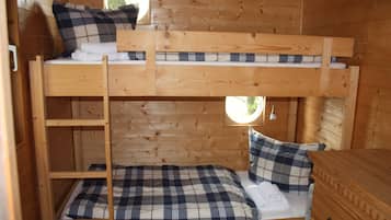 Une chambre avec un lit superposé, un intérieur en bois, une petite fenêtre et une commode.