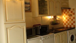 A compact kitchen with white cabinetry, a microwave, a dishwasher, and a washing machine. - COMFORTABLE SEA-FRONT PAVILION (Fleury)