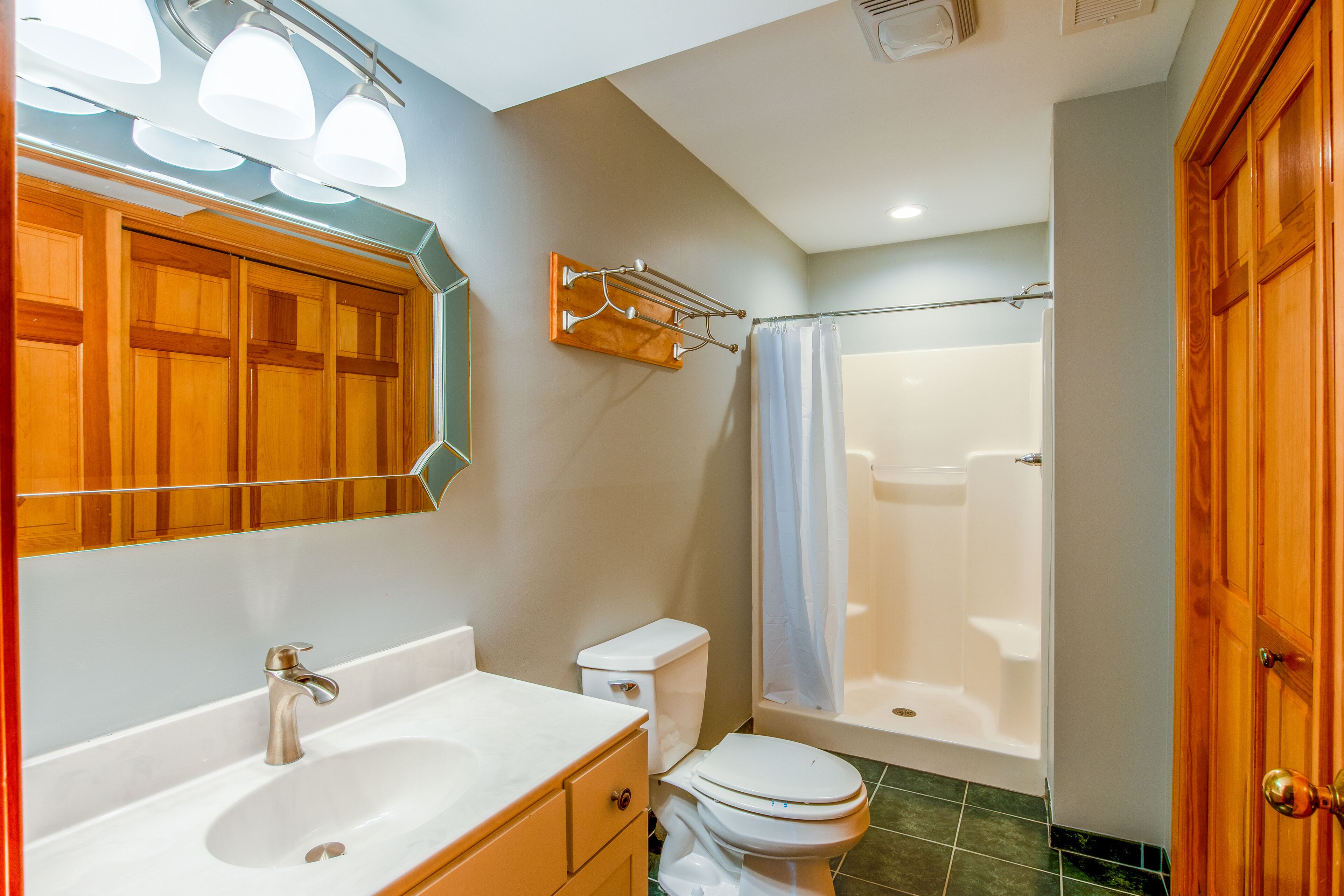 A bathroom with a sink, toilet, and shower area.