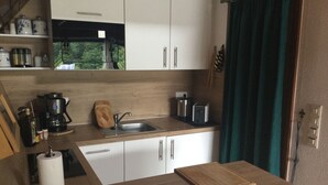 A compact kitchen with a sink, a coffee maker, a toaster, and a cutting board on the counter. - Quiet, cozy vacation home with fireplace, barbecue area and fantastic views (Hatzfeld (Eder))