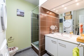 A bathroom with a shower, toilet, sink, and mirror.