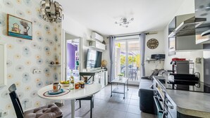 A modern kitchen with a dining area, a TV, and a balcony with a view.