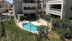 Ein Wohngebäude mit Schwimmbecken, umgeben von Grünflächen.