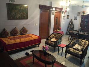 A living room with a sofa, two armchairs, a coffee table, and a dining table with chairs.
