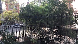 Un balcó amb plantes en testos, una barana de metall i vista al carrer.