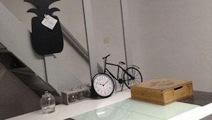 Eine moderne Küche mit weißer Arbeitsplatte, einer schwarzen Uhr, einem Fahrrad und einer Holzkiste.