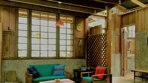 A room with a wooden ceiling, a green sofa, a wooden chair, a small table, and a window with a grid pattern. - Beachfront-rainforest tropical paradise retreat, Drake Bay, Osa Peninsula (Bahia Drake)
