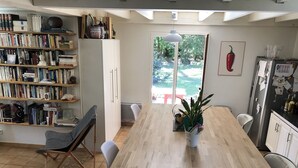 Una cocina moderna con una isla de madera, una estantería llena de libros y un refrigerador con imanes y notas.