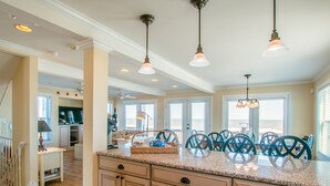 A spacious kitchen with granite countertops, wooden cabinets, and pendant lighting. - 2875 - MOJO'S, Duck Beachfront Home w/ Pool Table & Views (Duck)
