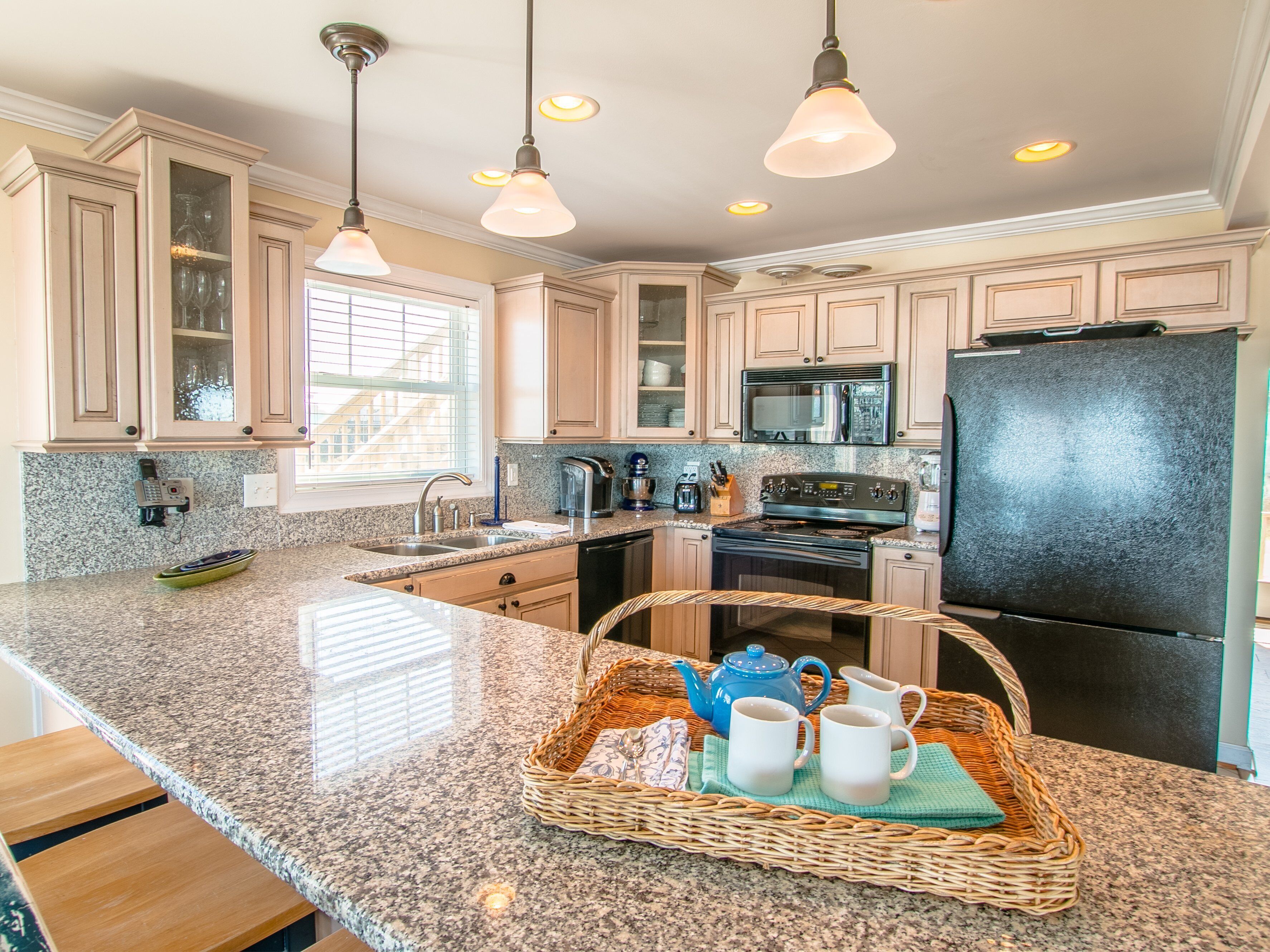 A kitchen with granite countertops, stainless steel appliances, and light wood cabinets.