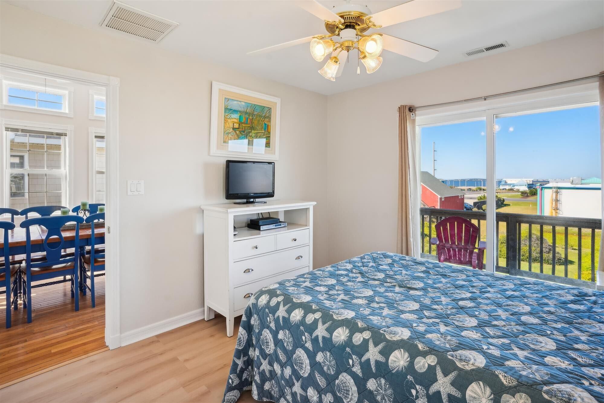 A bedroom with a bed, a TV on a dresser, a chair, and a balcony with a view.