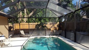 An outdoor swimming pool with a covered area, surrounded by a wooden fence and trees. - Stunning Naples home with pool, bike to the Gulf at Wiggins or Vanderbilt.  (Naples)