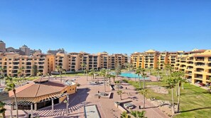Un resort con edificios de varios pisos, un área de piscina central y asientos al aire libre.