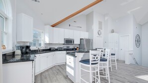 A modern kitchen with white cabinets, a black countertop, and a wooden ceiling beam. - 2310 - Aegean Breeze, Corolla Estate w/ Heated Pool, Spa & Billiards (Corolla)