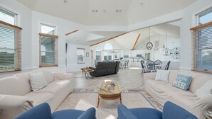 A spacious living area with a high ceiling, wooden beams, and large windows with blinds. - 2310 - Aegean Breeze, Corolla Estate w/ Heated Pool, Spa & Billiards (Corolla)