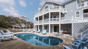 A two-story building with a pool, outdoor seating, and a covered patio area. - 2310 - Aegean Breeze, Corolla Estate w/ Heated Pool, Spa & Billiards (Corolla)