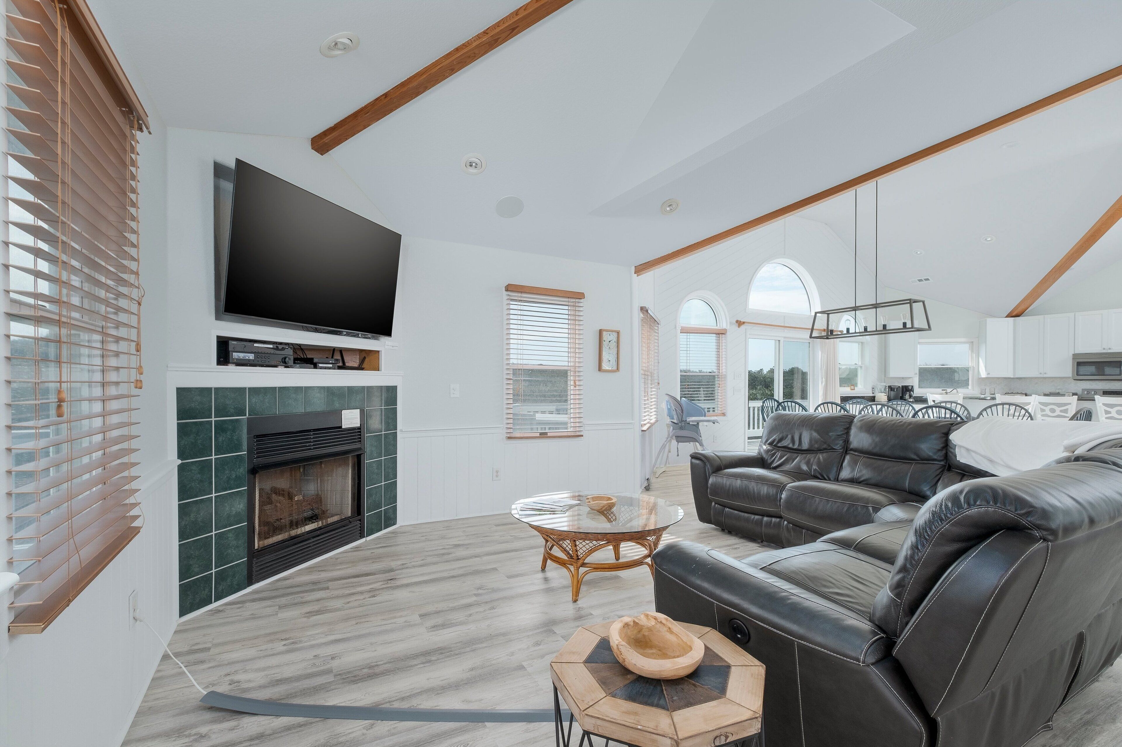 A modern living room with a fireplace, leather sofa, and a flat-screen TV.