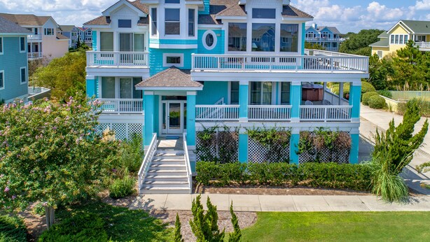 A two-story house with a balcony on the second floor, surrounded by greenery. - 1600 - Bases Loaded - Spacious Buck Island Retreat in Corolla (Corolla)