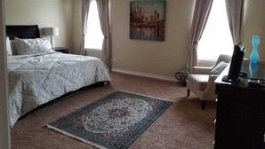 A bedroom with a bed, a desk, a chair, a painting, and a rug. - Lackland AFB/Seaworld (1) (San Antonio)