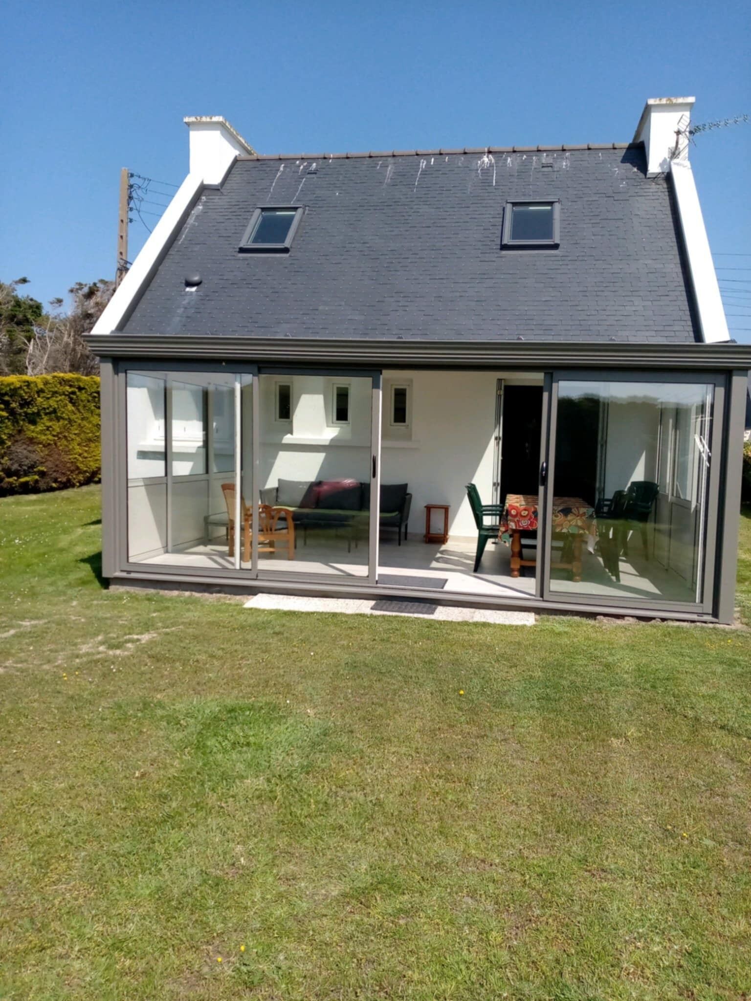 Een modern huis met een grote glazen gevel, een schuin dak en een klein balkon.