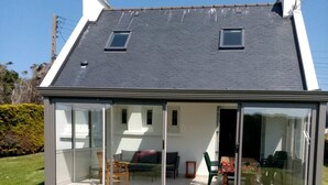 Een modern huis met een grote glazen gevel, een schuin dak en een klein balkon.