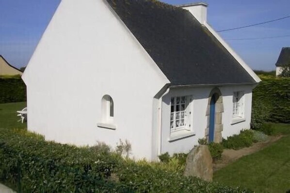 A white house with a steep roof, a small porch, and a window with a blue door. - Nice house located in l'Ile Grande, Granit Rose coast (Pleumeur-Bodou)