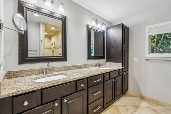 A bathroom with a double sink vanity, dark cabinets, and a large mirror.
