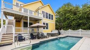 Ein zweistöckiges Haus mit Pool, Gartenmöbeln und einer überdachten Terrasse.