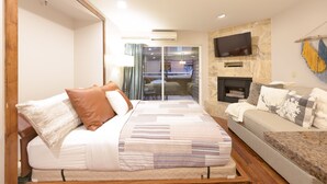 Une chambre d’hôtel moderne dotée d’un grand lit, d’un canapé, d’une télévision à écran plat et d’une cheminée.