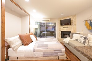 Relax in a spacious room with a large bed, sofa, and flat-screen TV, plus a fireplace for a cozy ambiance.